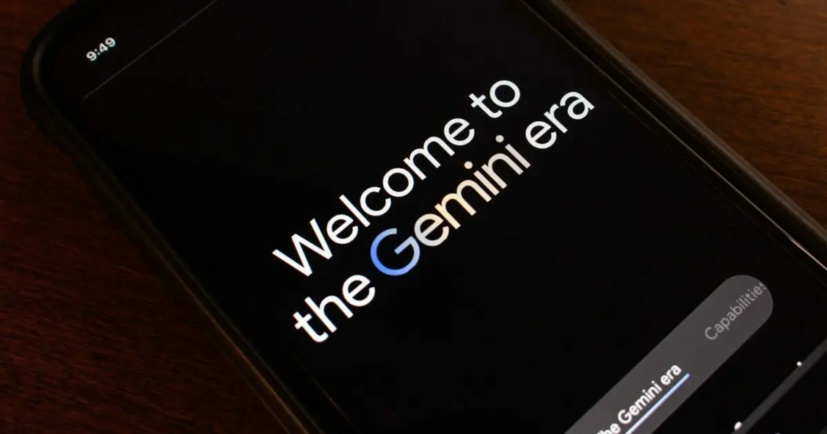 Imagem de um smartphone exibindo a mensagem "Welcome to the Gemini era" na tela. A palavra "Gemini" destaca-se com a letra "G" em azul, remetendo à identidade visual do Google. O dispositivo está sobre uma superfície de madeira, e a tela tem fundo preto com texto em branco, conferindo um design moderno e minimalista