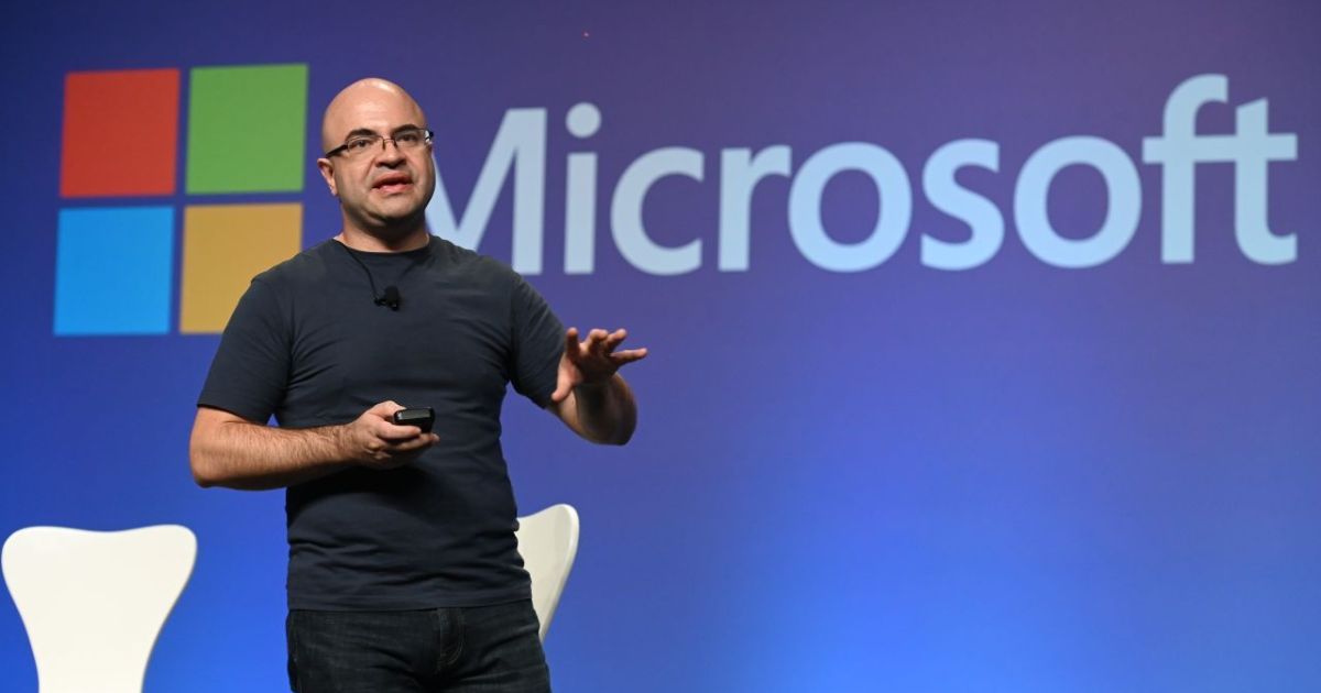 Marcondes Farias, líder do Microsoft Technology Center (MTC), apresentando em um evento. Ele está no palco com camiseta preta e óculos, falando ao público com o logotipo da Microsoft ao fundo em um grande telão azul (marcondes farias, microsoft, innovation hub)