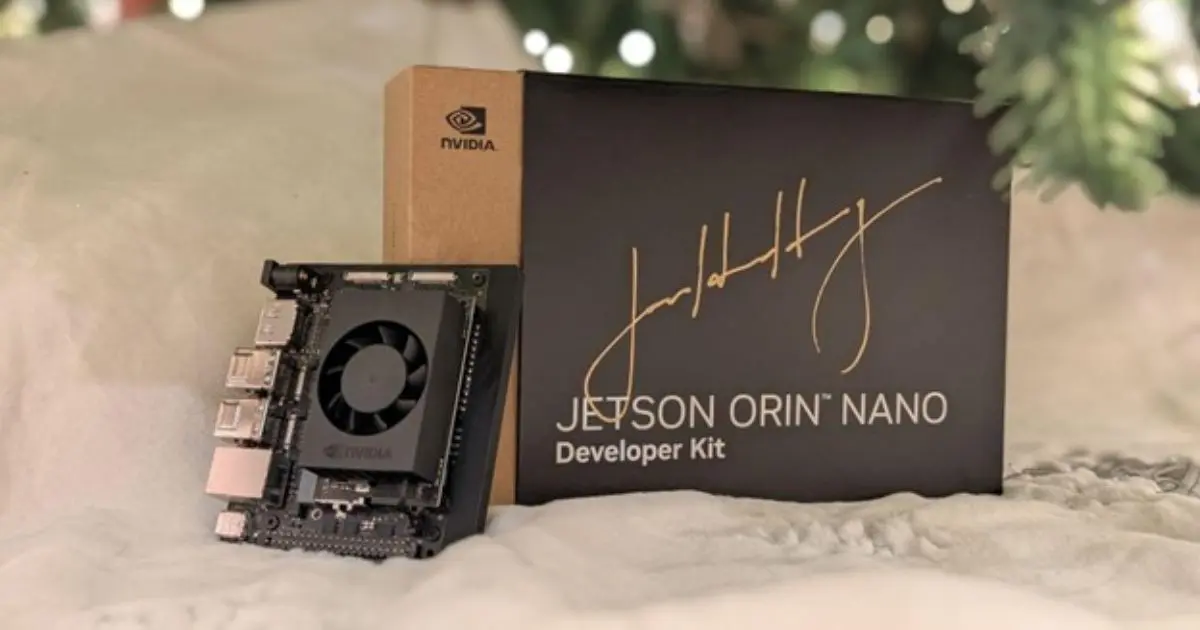 Kit de desenvolvimento NVIDIA Jetson Orin Nano exibido ao lado de sua caixa preta com assinatura estilizada. A placa apresenta conectores, um cooler e componentes visíveis, representando tecnologia voltada para inteligência artificial e projetos de hardware (nvidia, genai, jetson orin nano, developer kit)