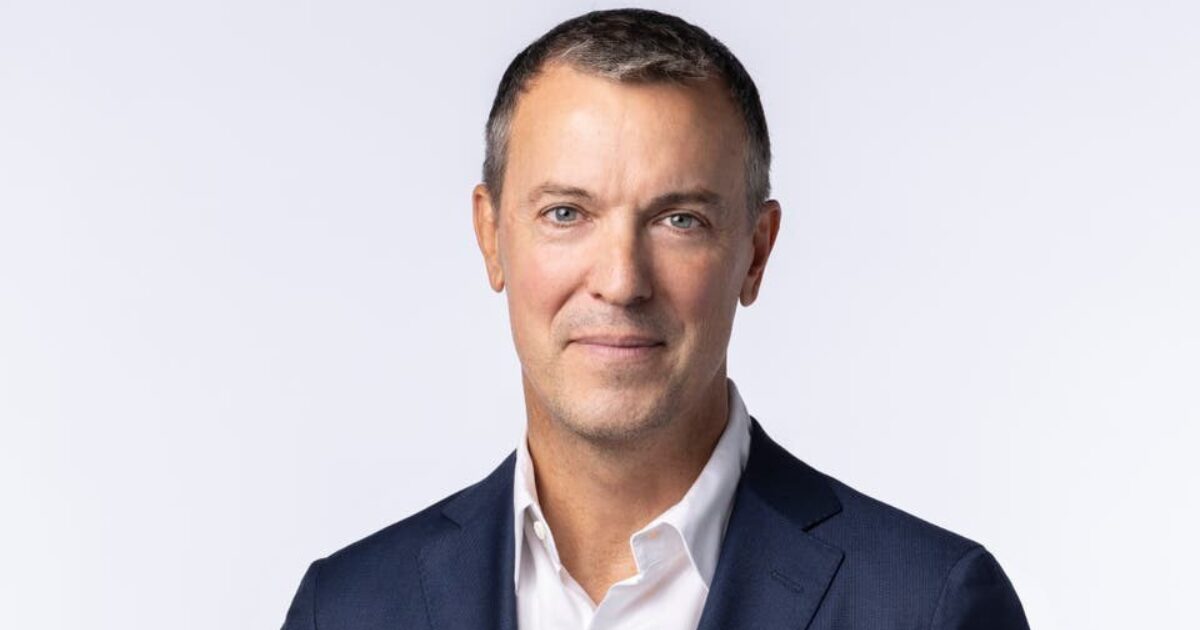 Michael Komasinski, novo CEO da Criteo, em destaque. Ele está usando um terno azul escuro e camisa branca, com uma expressão séria e confiante. O fundo é branco, destacando o profissional e transmitindo uma imagem de liderança e profissionalismo.