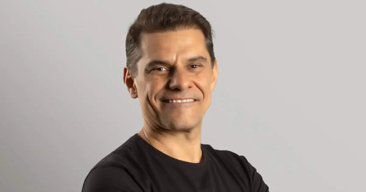 Paulo Secco, CEO da Mignow, sorrindo em um retrato de meio corpo com fundo neutro, vestindo uma camisa preta