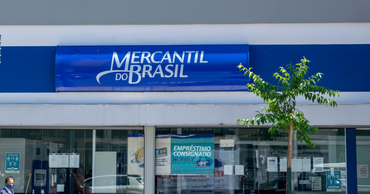 Fachada de uma agência do banco Mercantil do Brasil com o letreiro azul destacado e uma árvore em frente à entrada. A imagem transmite o ambiente externo da instituição financeira (google cloud)