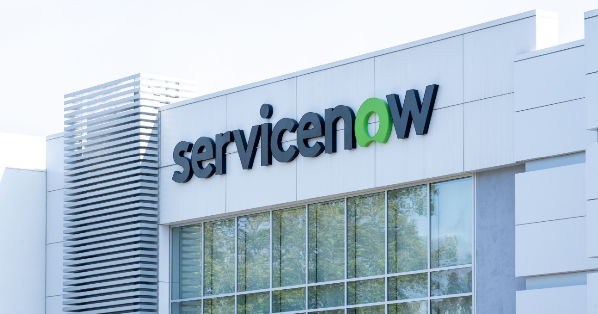 Fachada de um prédio corporativo da ServiceNow, com o logotipo da empresa em destaque. O design do edifício é moderno, com linhas limpas, janelas amplas e detalhes em branco, refletindo um ambiente empresarial contemporâneo (parceiros, projetos)